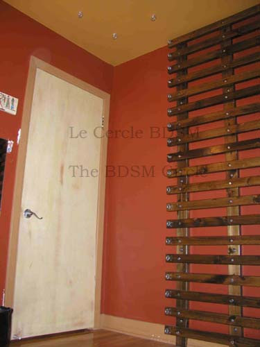 photo du mur gauche en entrant, qui comprend le rack de bondage et vue partielle du mur de la porte d'entre