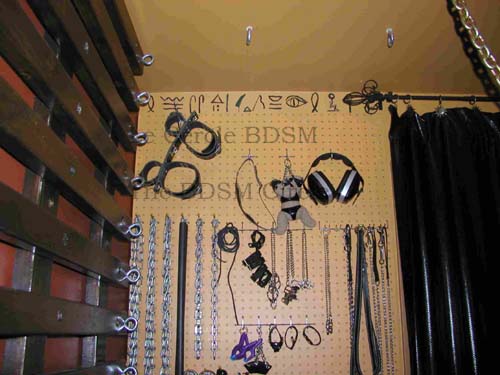 picture of the left upper part of the outside wall with all the BDSM toy on the pegboard